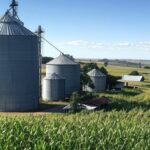 Paisagem agrícola no norte do Paraná com silos e campos de cultivo, representando aquisição de unidades pela Coamo.