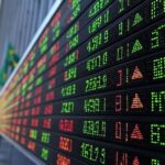 Painel de bolsa de valores em São Paulo mostrando recordes asiáticos impulsionados por ações de defesa e efeito Maduro.