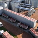 Frigorífico brasileiro com caminhões de carne bovina para exportação ao Vietnã, em paisagem rural do Brasil.