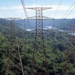 Torres de transmissão na floresta amazônica representando o Programa Energias da Amazônia com interligações ao SIN, beneficiando 500 mil consumidores.