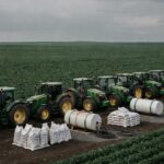 Plantação de soja no Brasil com tratores e fertilizantes, ilustrando alta nos preços de ureia e diesel devido a tensões internacionais.