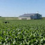Paisagem rural brasileira com centro de tecnologia agrícola moderna, plantações e drones, representando inovação no campo.