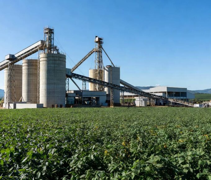 Instalação industrial de esmagamento de soja em Ponta Grossa, com campos de plantação ao fundo.
