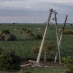 Paisagem rural brasileira com postes de energia danificados em plantação de soja, representando falhas no fornecimento.