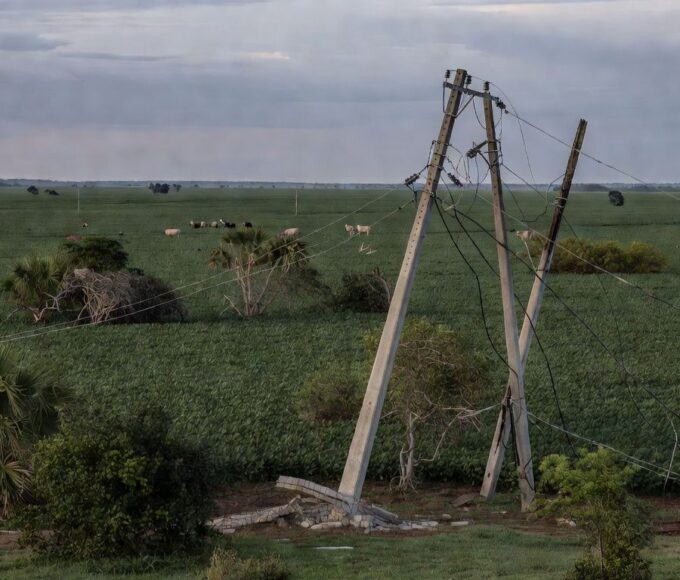 Paisagem rural brasileira com postes de energia danificados em plantação de soja, representando falhas no fornecimento.