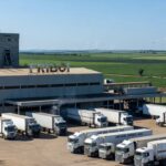 Frigorífico brasileiro com caminhões de exportação de carne para os EUA em paisagem rural.