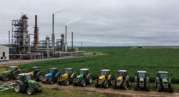 Refinaria de petróleo no RS com campos de soja ao fundo, alertando para possível desabastecimento de diesel.