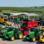 Feira Agrishow 2024 com máquinas agrícolas e campos no interior de São Paulo, expressando otimismo no agro brasileiro apesar de desafios.